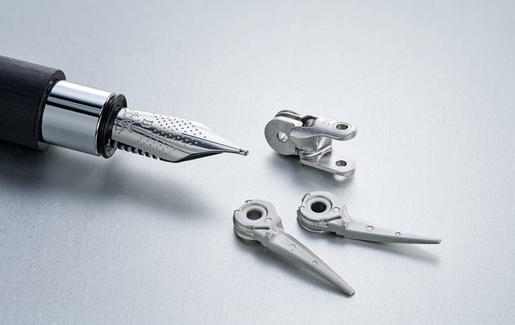 Fig. 10 The tip core (upper part) is an articulated piece of an instrument control system for robot-assisted surgery, made from 17-4 PH stainless steel. The lower parts form a pair of scissors that are used as a cutting instrument in robot-assisted surgery and are made of AISI 420 martensitic stainless steel (© 2023 Distalmotion. Image used with permission)
