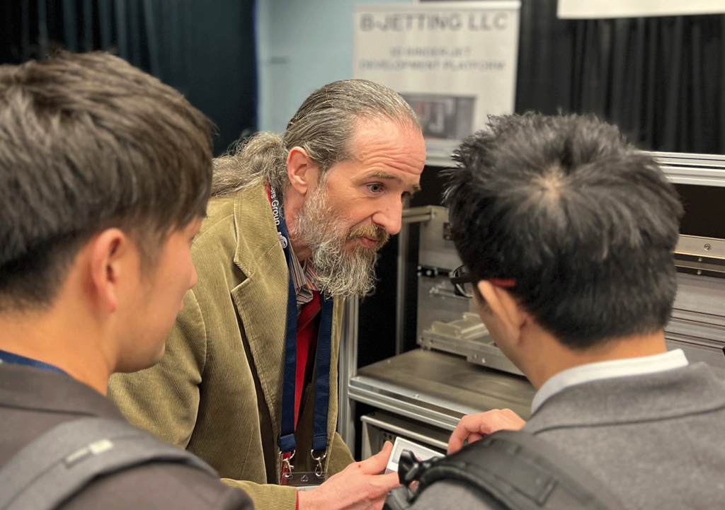 Fig. 1 Dan Brunermer speaking with booth visitors at AMUG 2025 