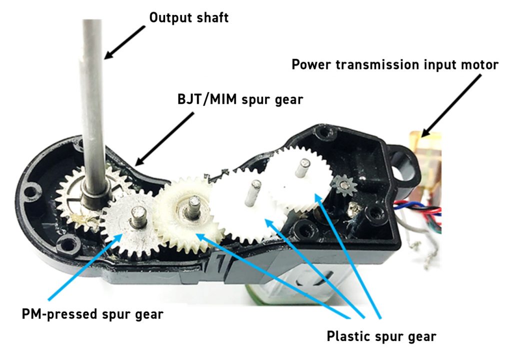Fig. 2 Gearbox assembly with BJT/MIM spur gear, PM-pressed gear, and plastic spur gears driven by an input motor
