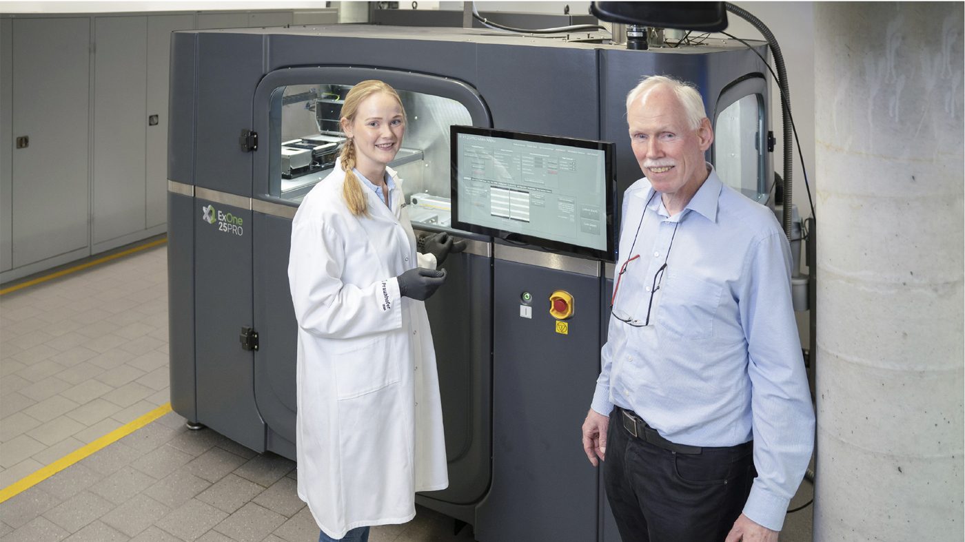 Fig. 7 Frank Petzoldt with Lea Reineke, a PhD student at Fraunhofer IFAM, in front of an ExOne metal Binder Jetting machine at Fraunhofer IFAM, Bremen (Courtesy Fraunhofer IFAM/ExOne)